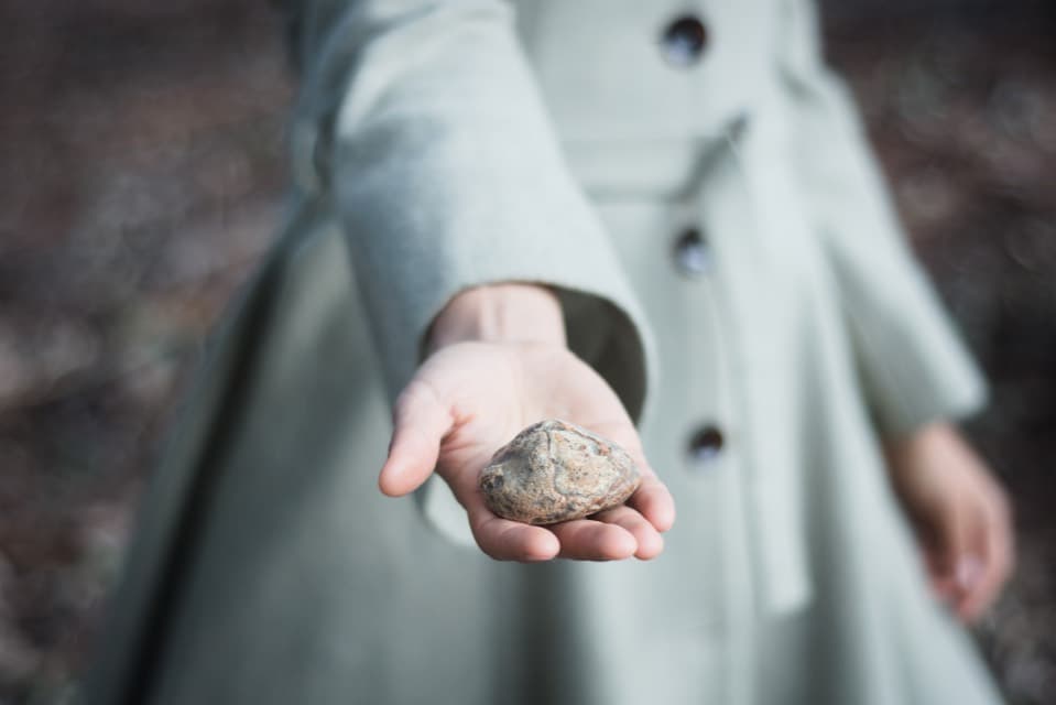 Caroluz sosteniendo una piedra en el bosque